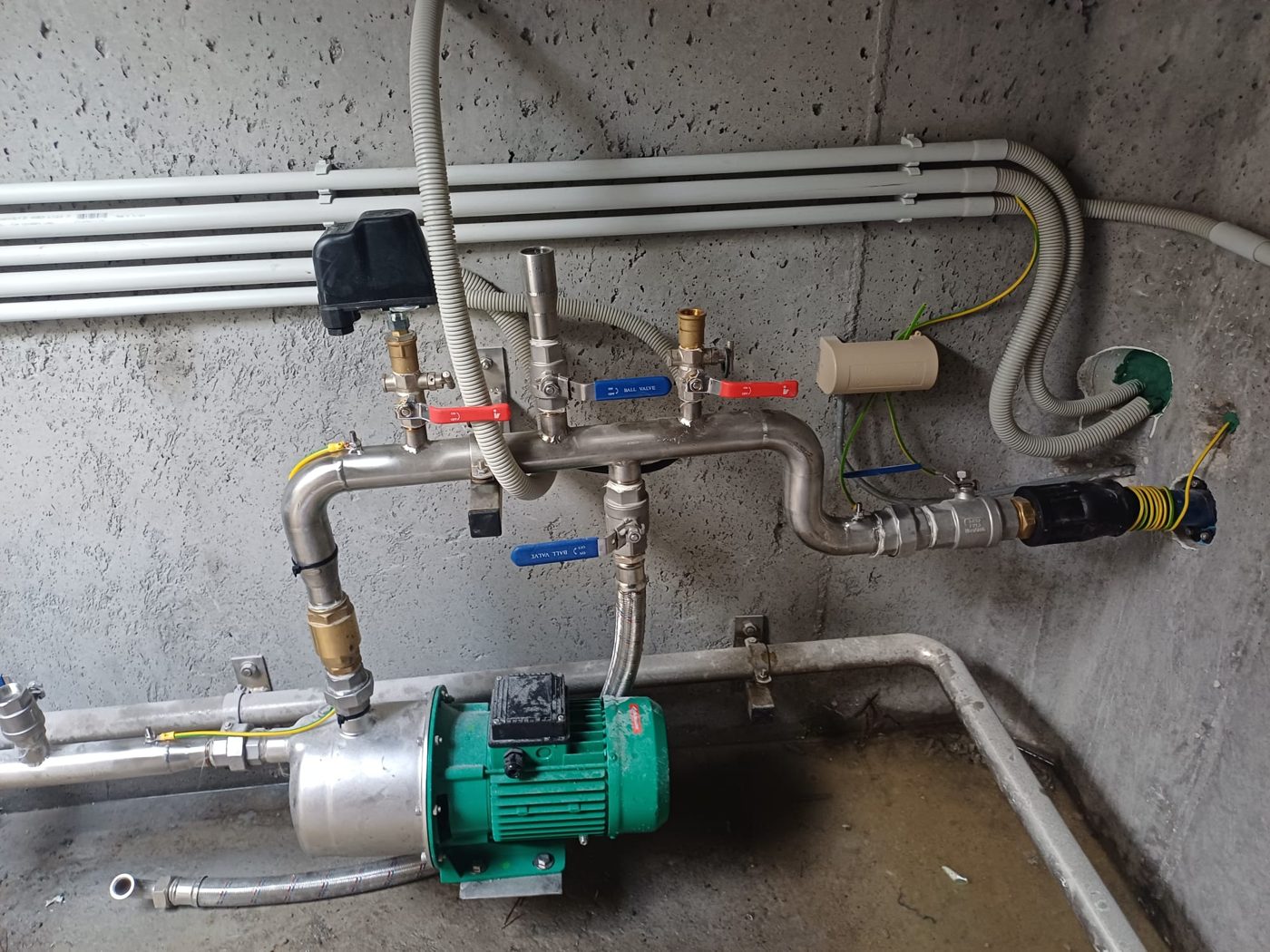 Čerpadlo s nerezovým potrubím a elektroinstalací vedenou v chráničkách po betonové stěně